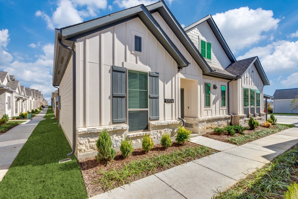 a white house with green shutters and a sidewalk