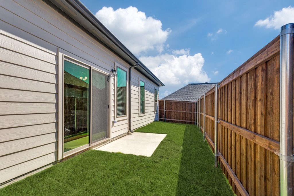 the backyard of a home with a wooden fence and grass