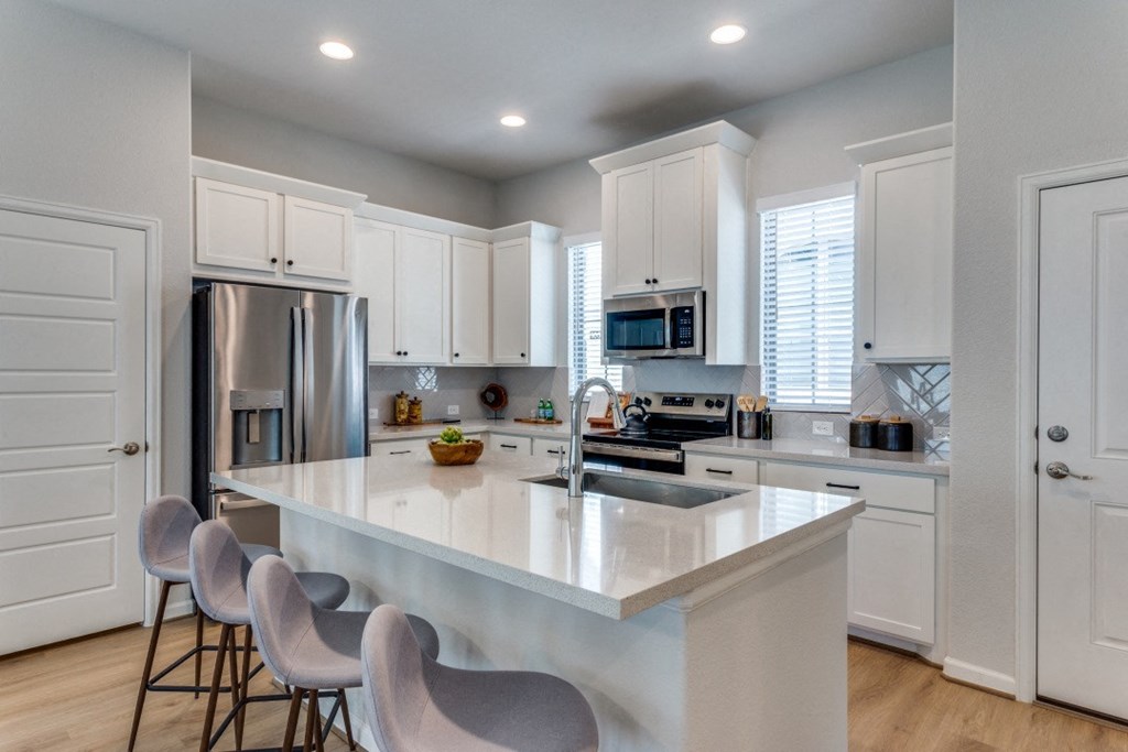 an open kitchen with a large island and white cabinets