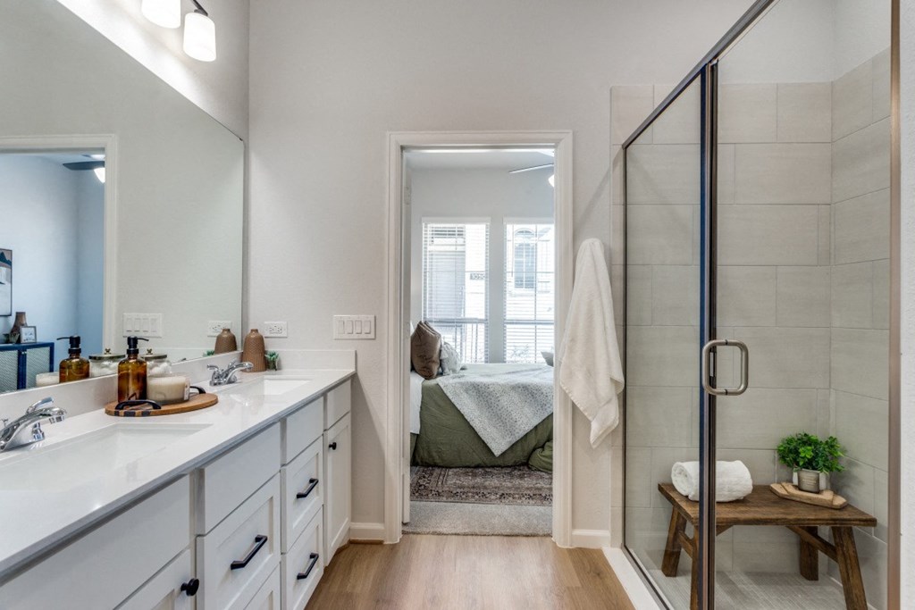 a bathroom with two sinks and a shower and a bedroom with a bed