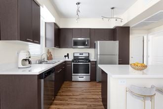 a kitchen with white countertops and dark cabinets and stainless steel appliances