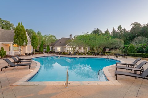 A large swimming pool surrounded by lounge chairs and trees.