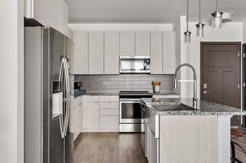 A modern kitchen with a refrigerator, sink, and stove.