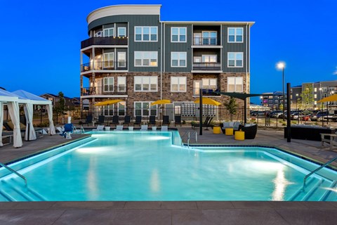 a swimming pool at night with a building in the background