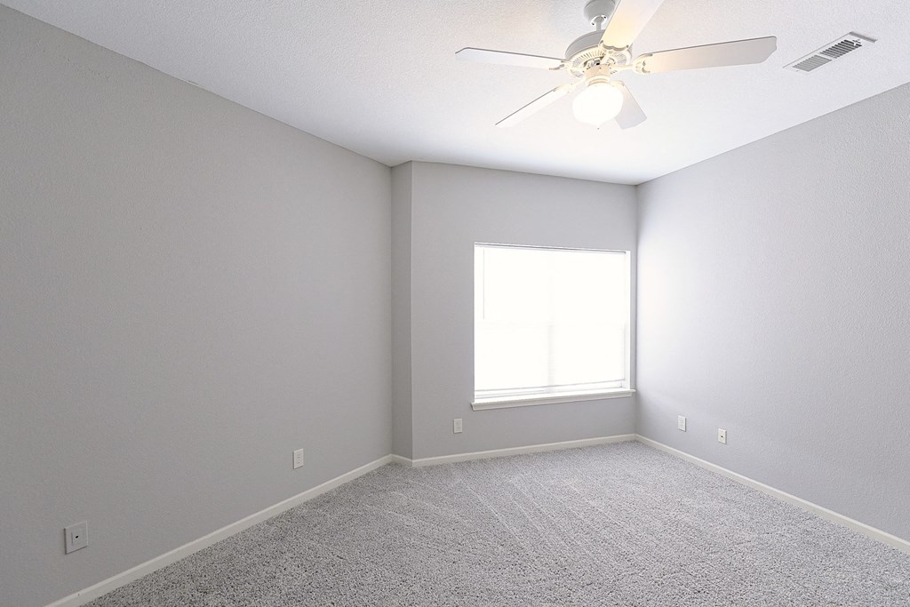 an empty room with a ceiling fan and a window