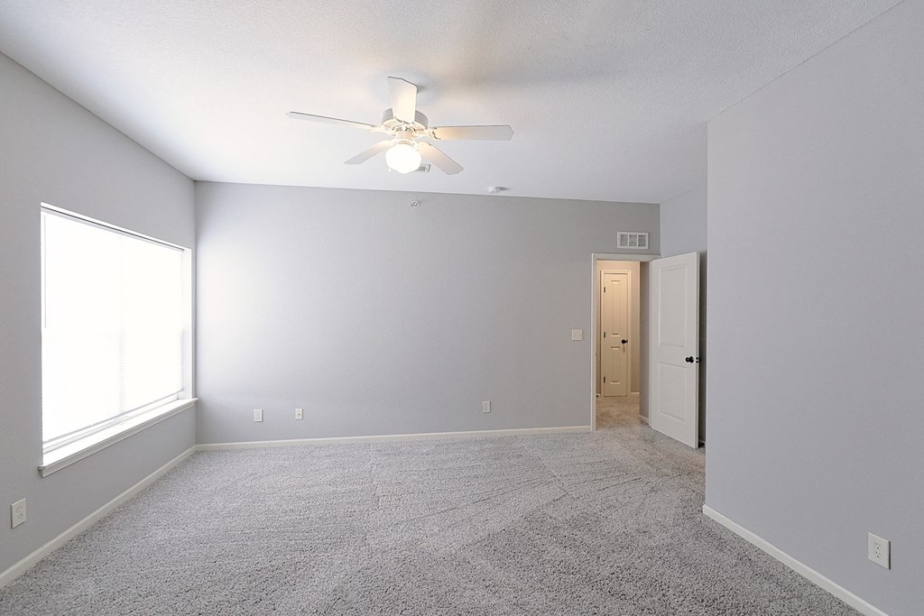 an empty living room with a ceiling fan and a window
