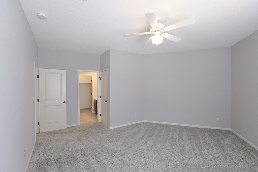 a spacious living room with gray walls and a ceiling fan