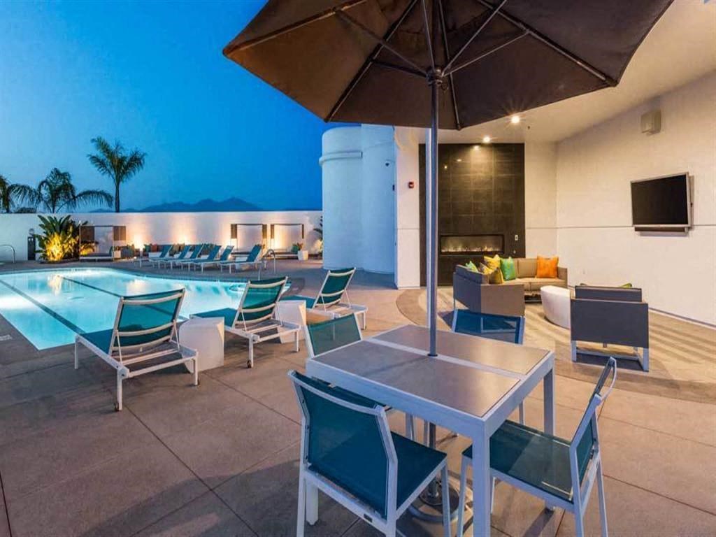 the pool and patio area of a hotel with tables and chairs