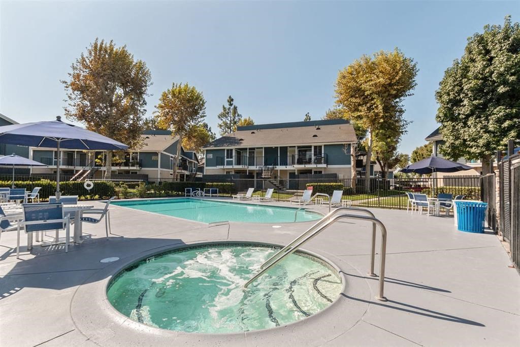 a hot tub with chairs and umbrellas and houses in the background