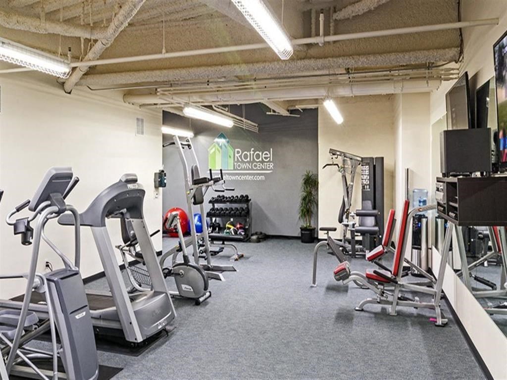 a gym with cardio equipment and a sign on the wall