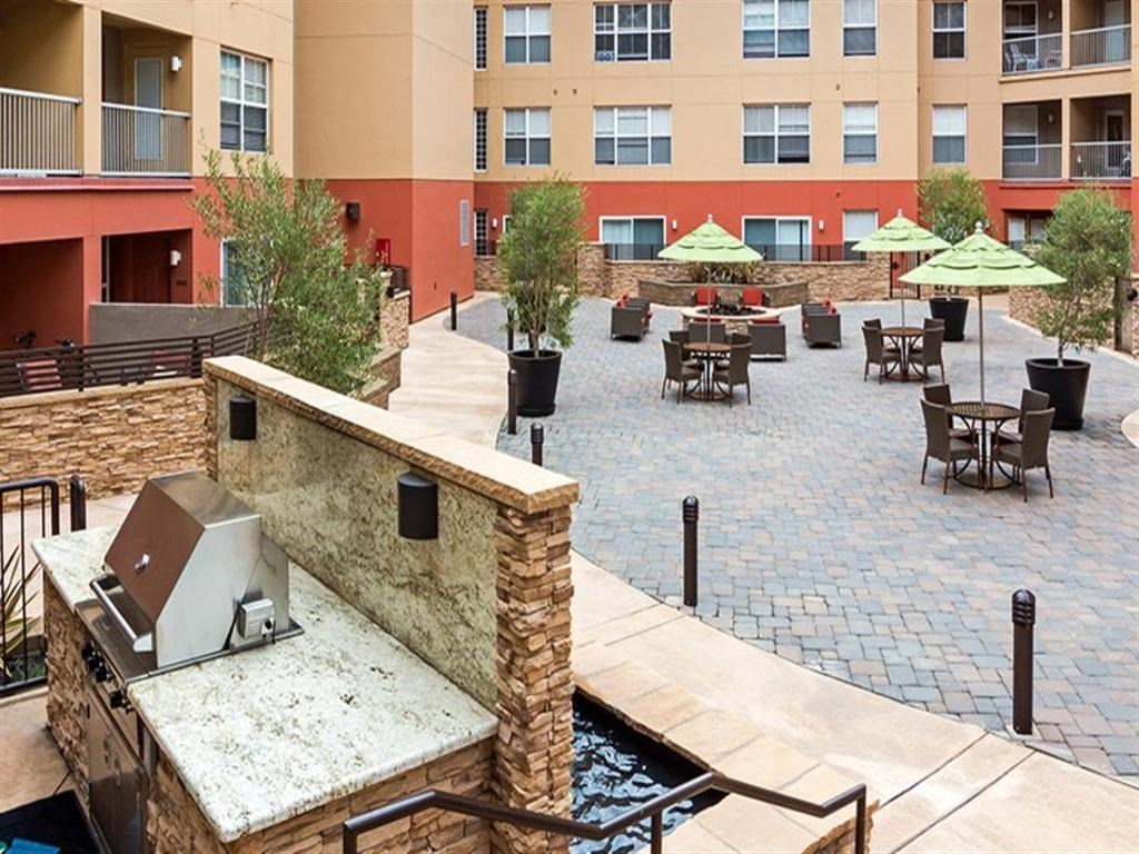 a patio with tables and umbrellas at a hotel with a fountain
