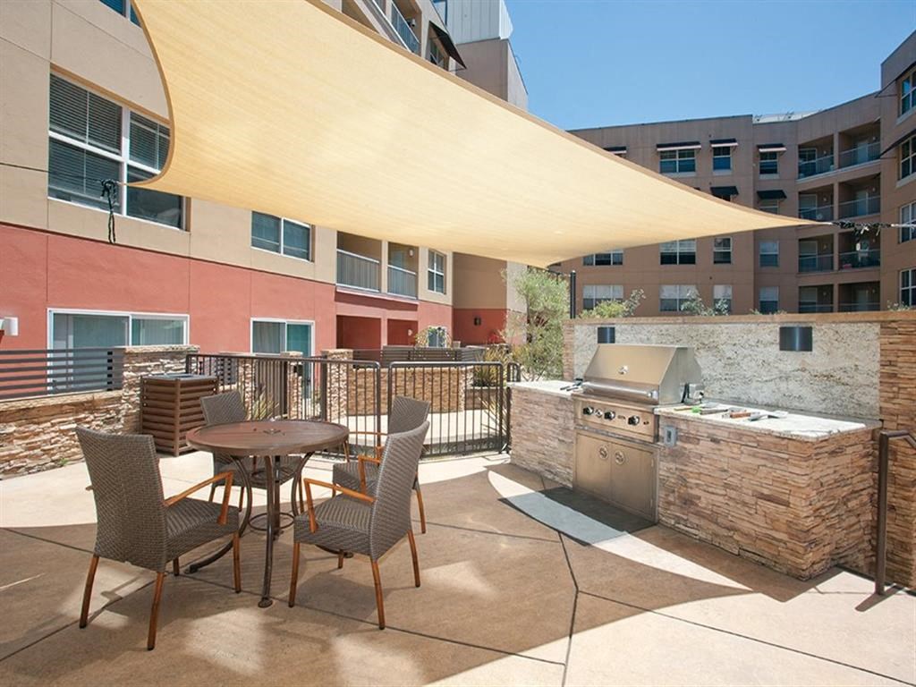 a patio with a table and chairs and a grill