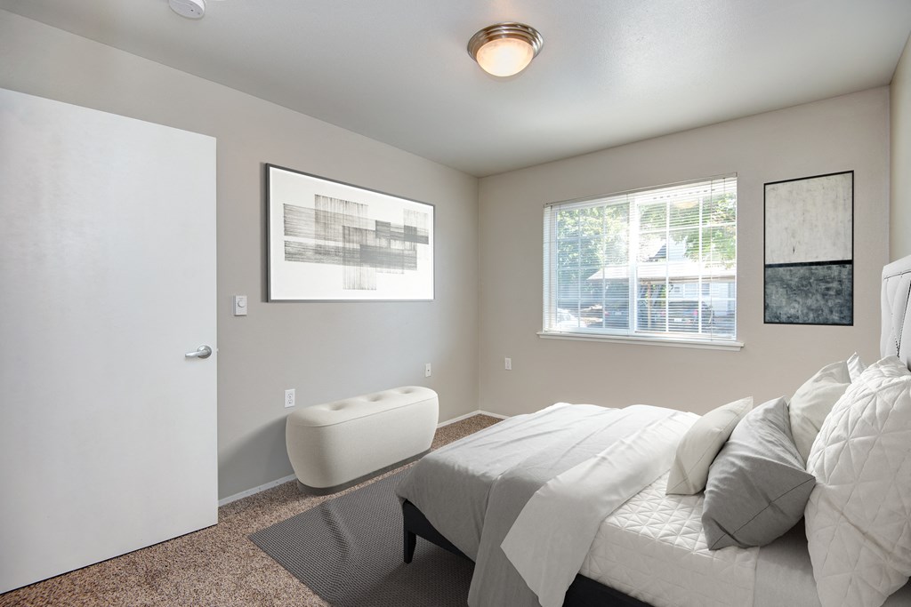 a white bedroom with a white bed and a white chair