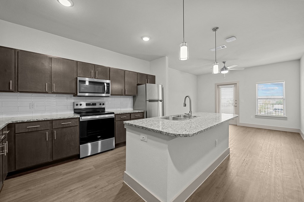 an open kitchen with a large island and stainless steel appliances
