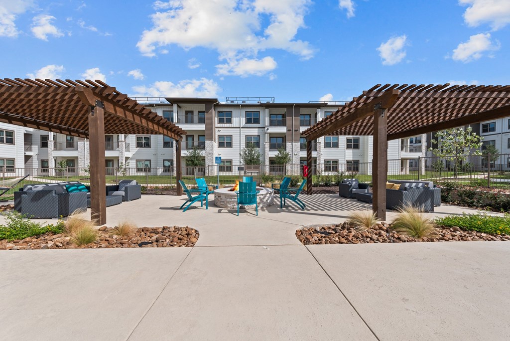 a patio with chairs and umbrellas in front of an apartment building