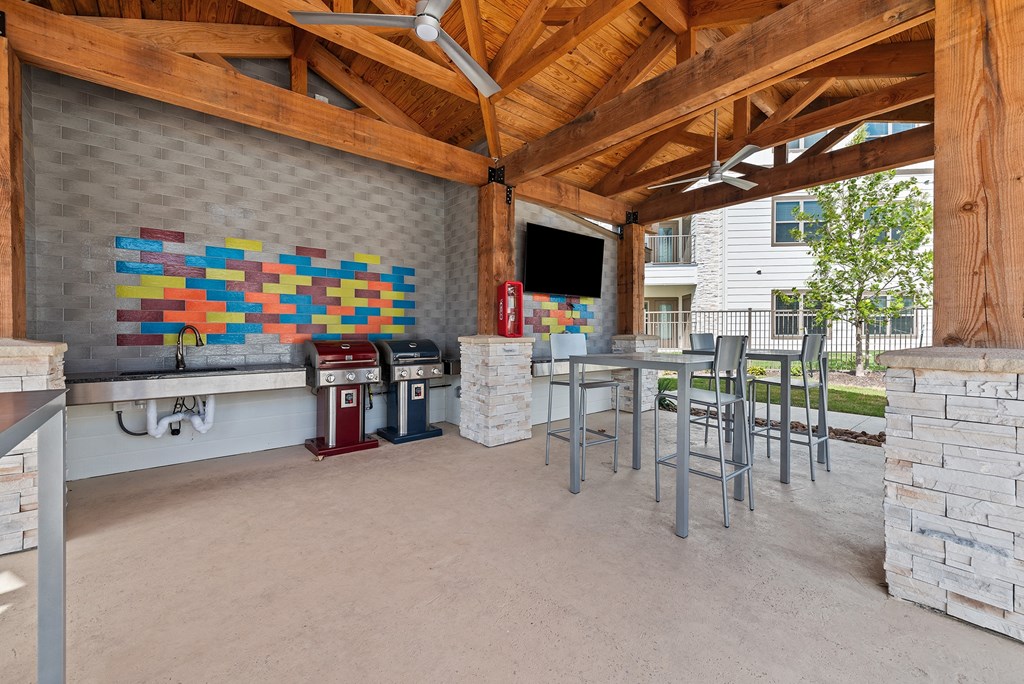 a covered patio with a bar and chairs and a grill