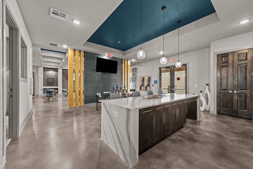 a kitchen with a large island and a living room with a table and chairs