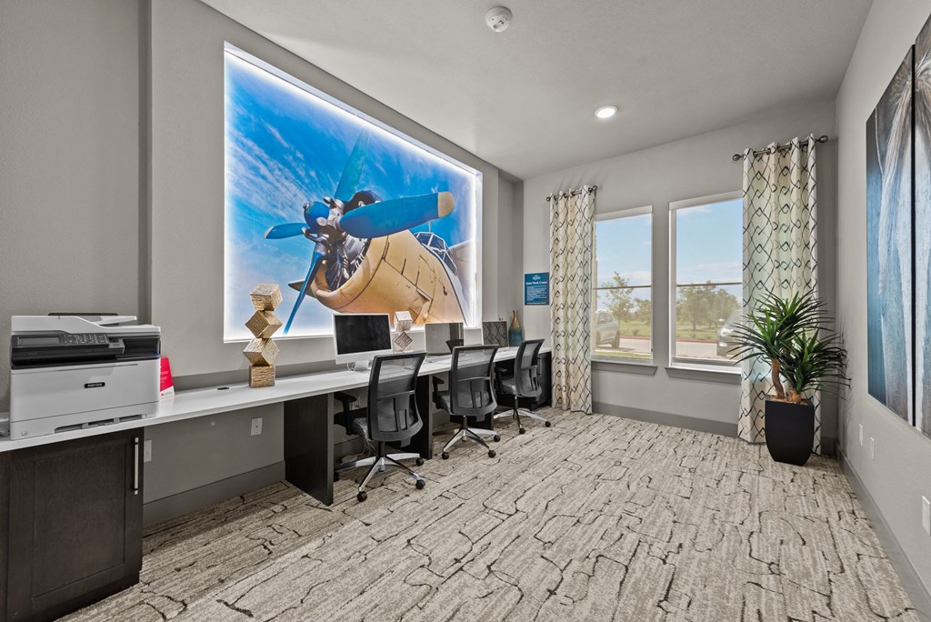 a conference room with desks and chairs and a large screen on the wall