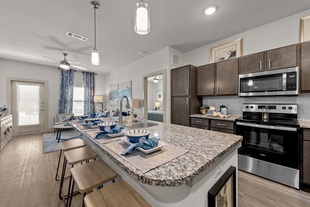 an open kitchen and dining area with a granite counter top and stainless steel appliances