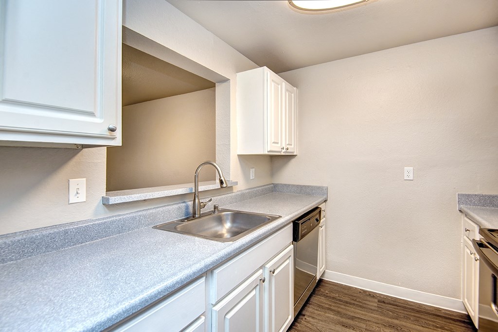 an empty kitchen with white cabinets and a sink
