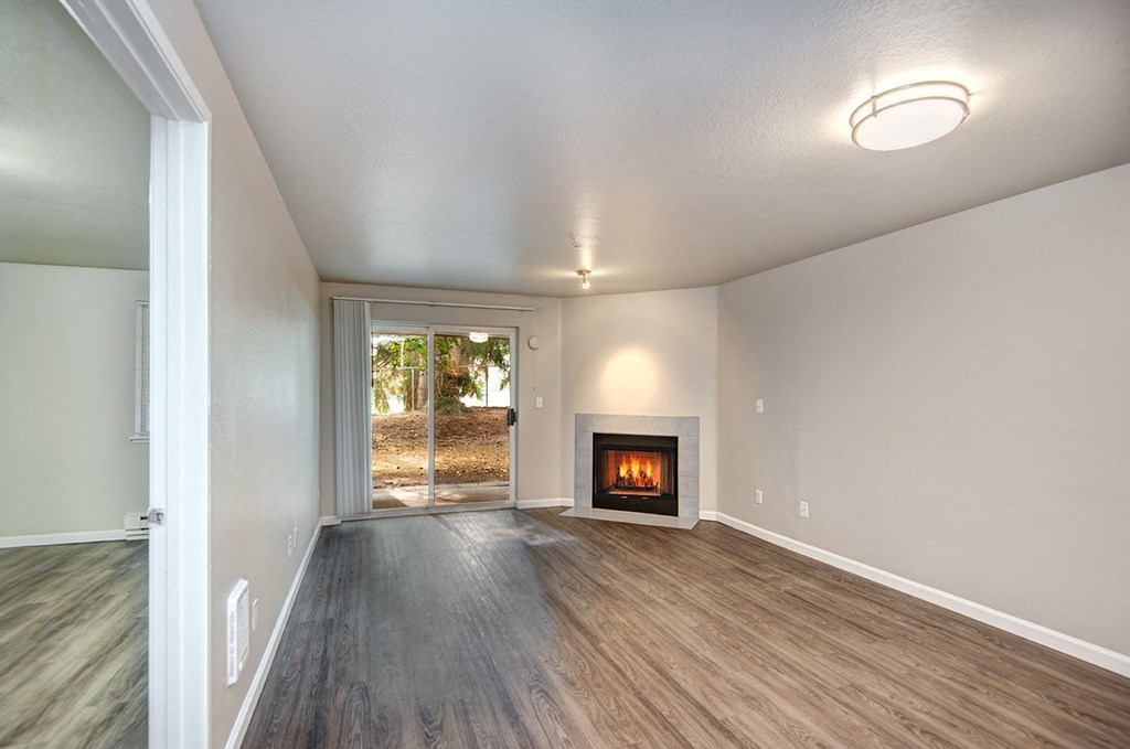 an empty living room with a fireplace and wooden floors