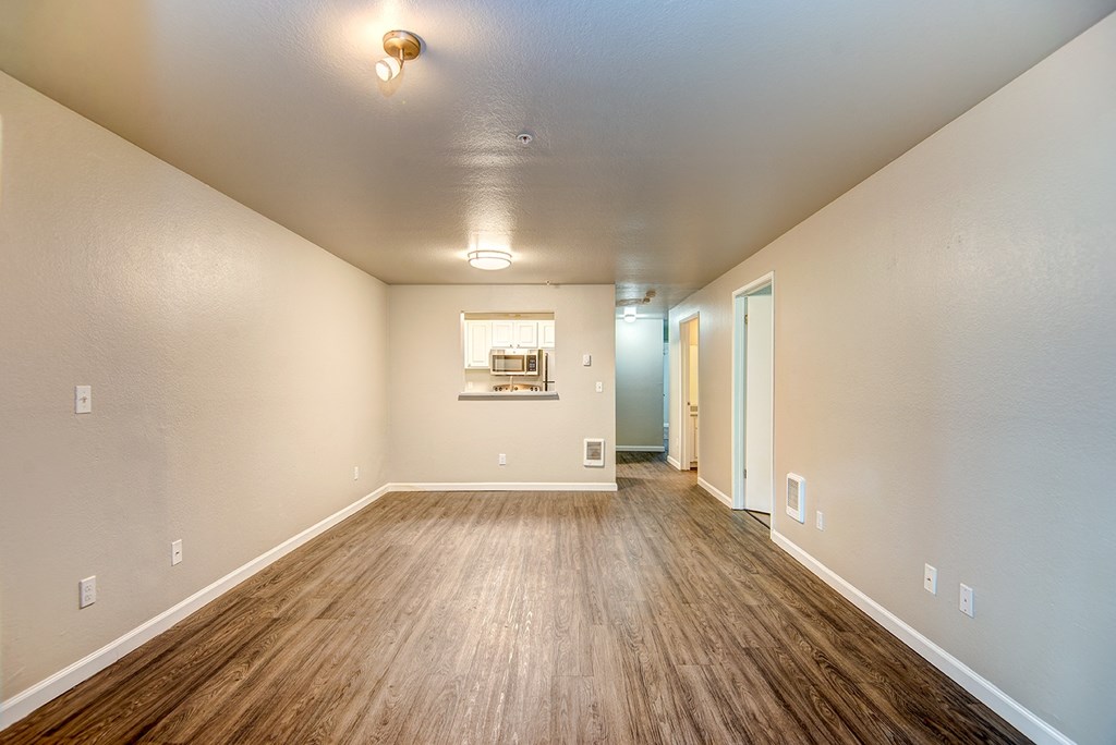 an empty living room with wood flooring and white walls