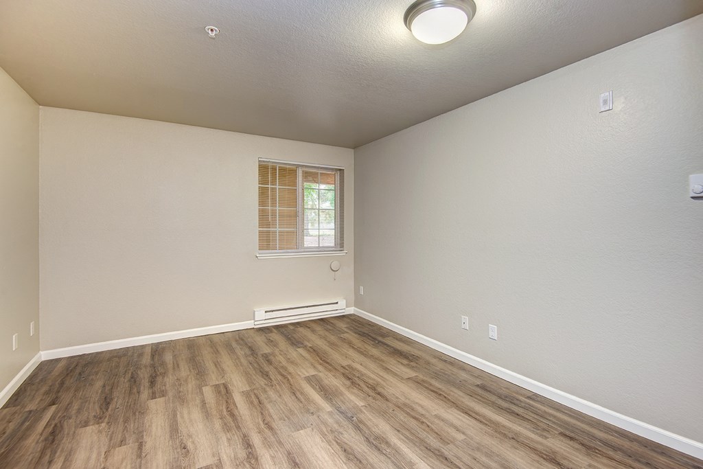 an empty living room with wood flooring and a window