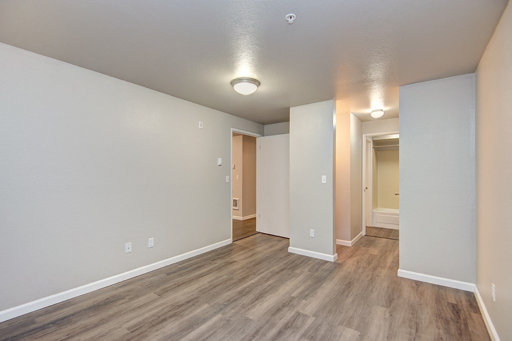 the living room and dining room of an apartment with wood floors and white walls