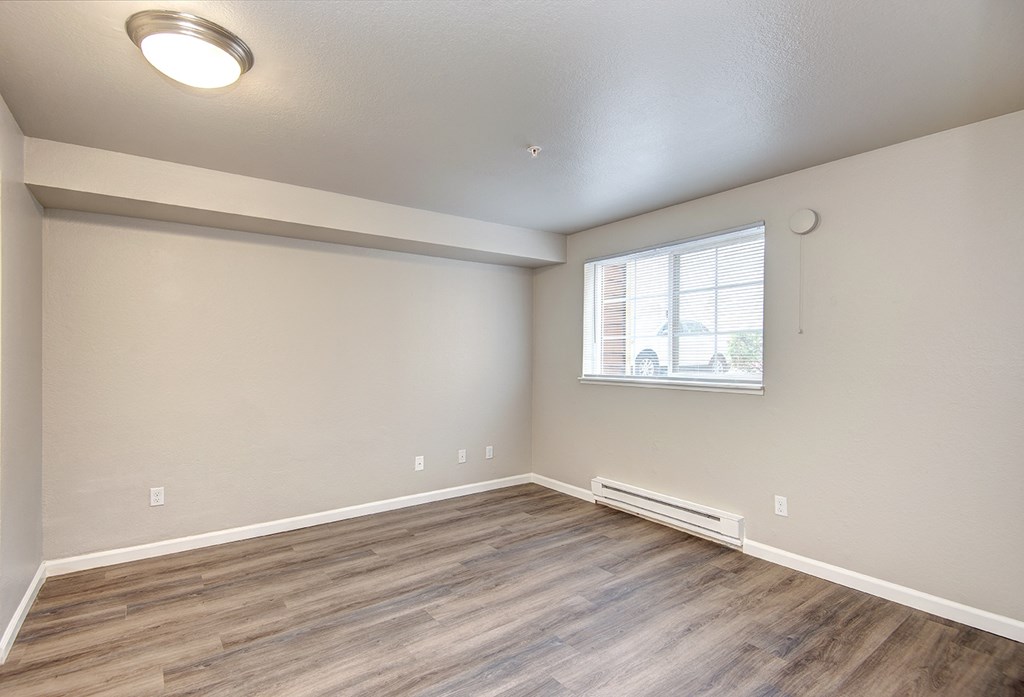 an empty living room with wood flooring and a window
