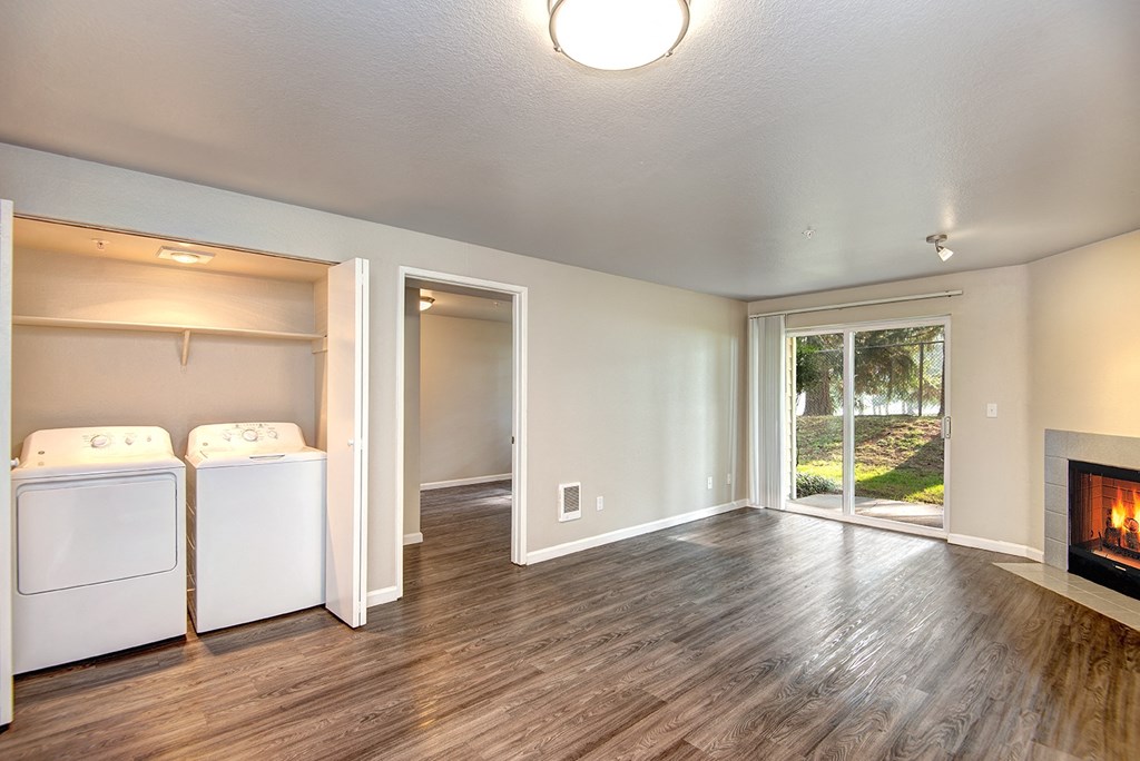 an empty living room with a fireplace and laundry room