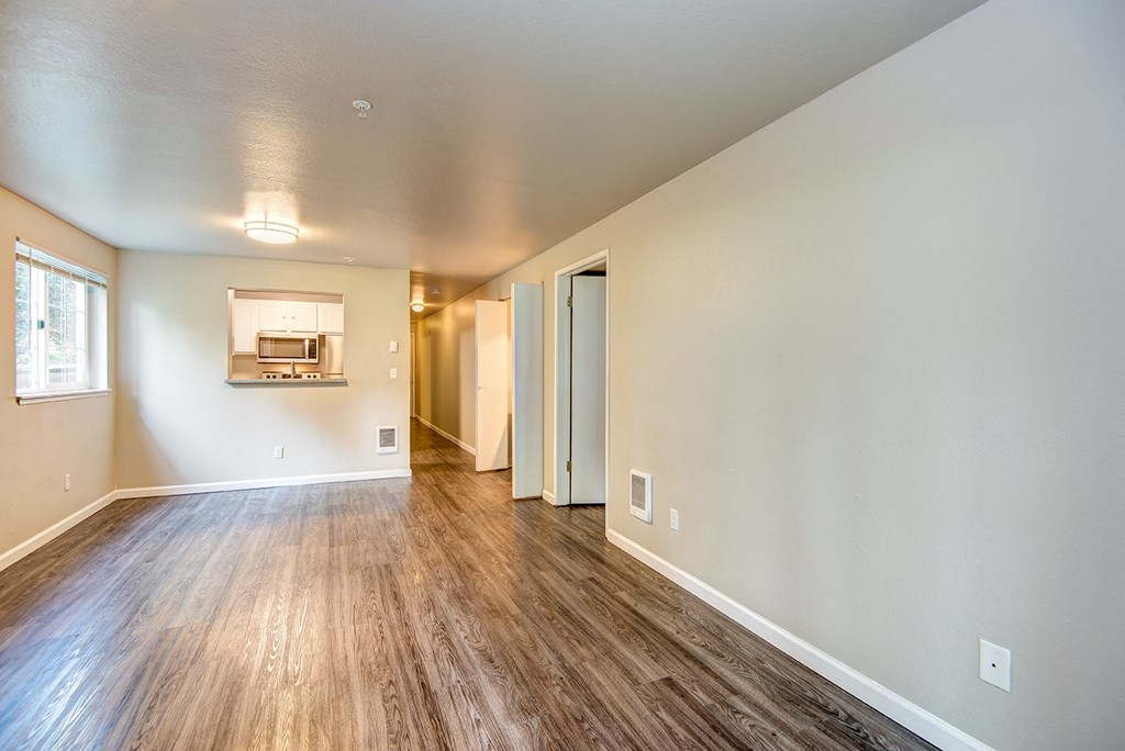 the living room and dining room of an apartment with wood flooring