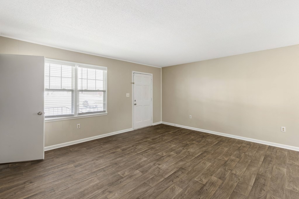 an empty living room with wood flooring and a window