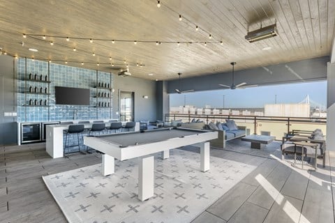 A modern outdoor patio with a pool table and bar area.