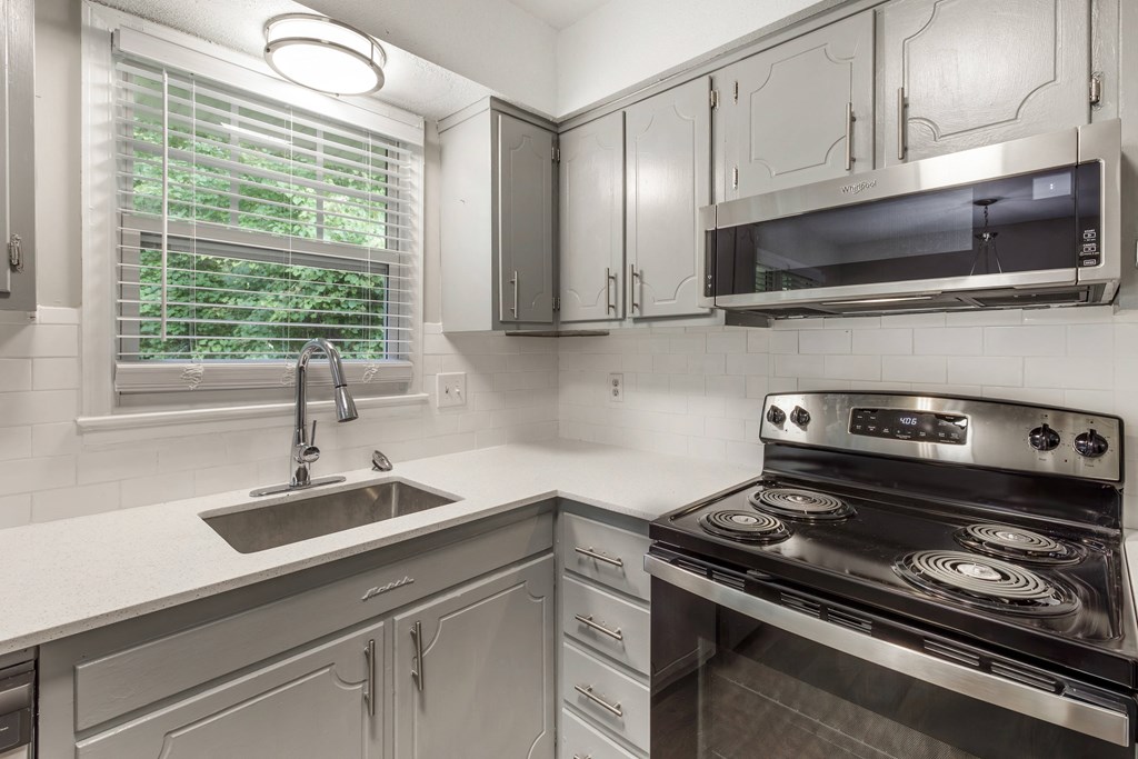 a kitchen with white cabinets and a sink and a stove