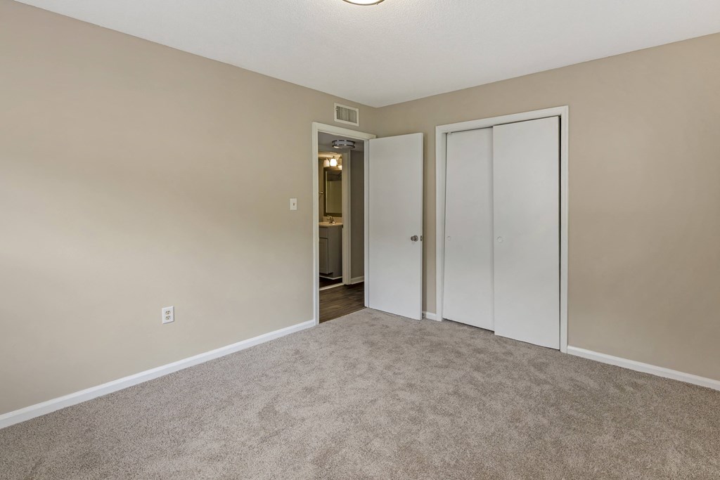 a bedroom with a closet and a door to a bathroom