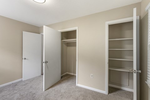 an empty bedroom with a closet and shelves