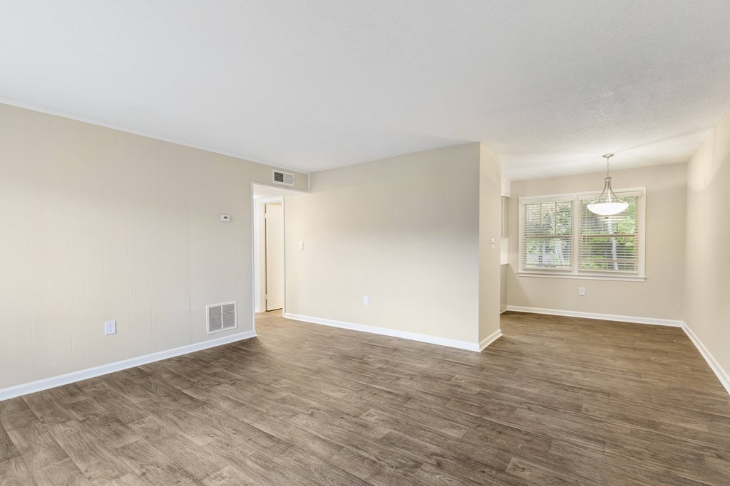 the spacious living room and dining room of an empty home with wood flooring