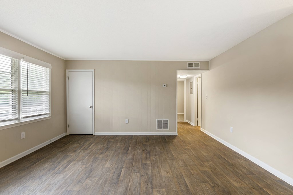 the living room and dining room of an apartment with wood floors and a large window
