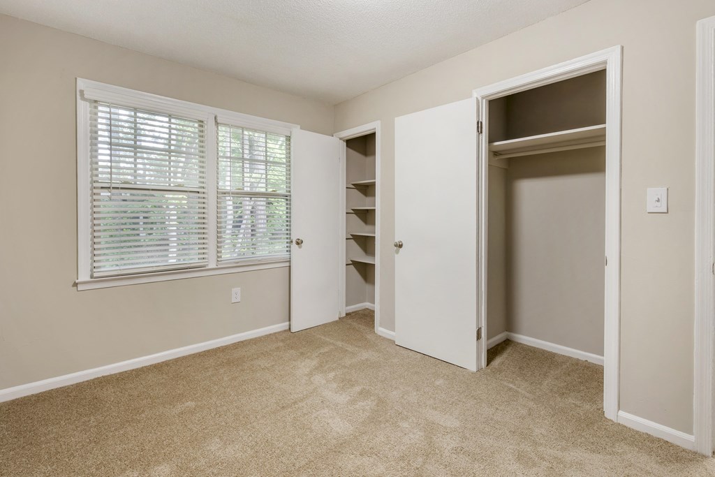 an empty bedroom with a closet and a large window