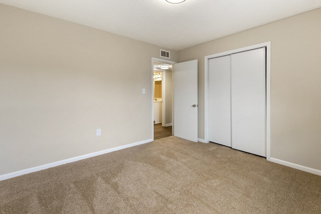 an empty living room with white doors and carpeting