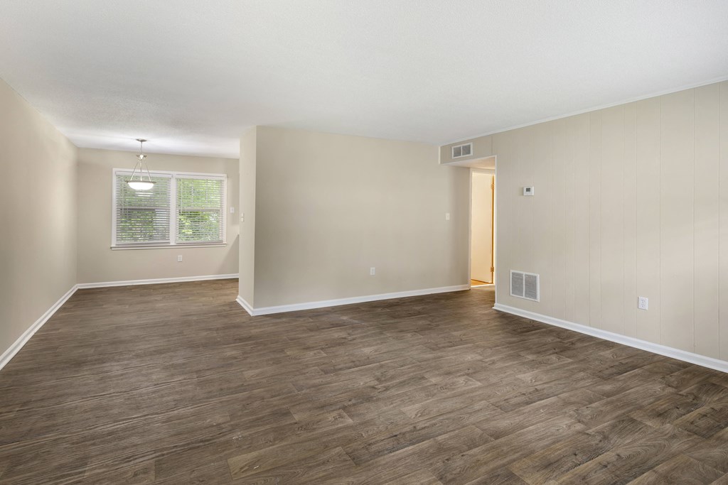 an empty living room with wood flooring and a window