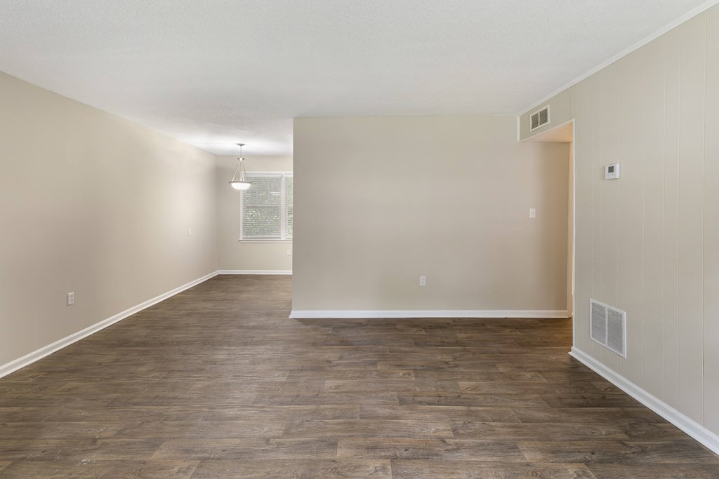 an empty living room with a wood floor and white walls