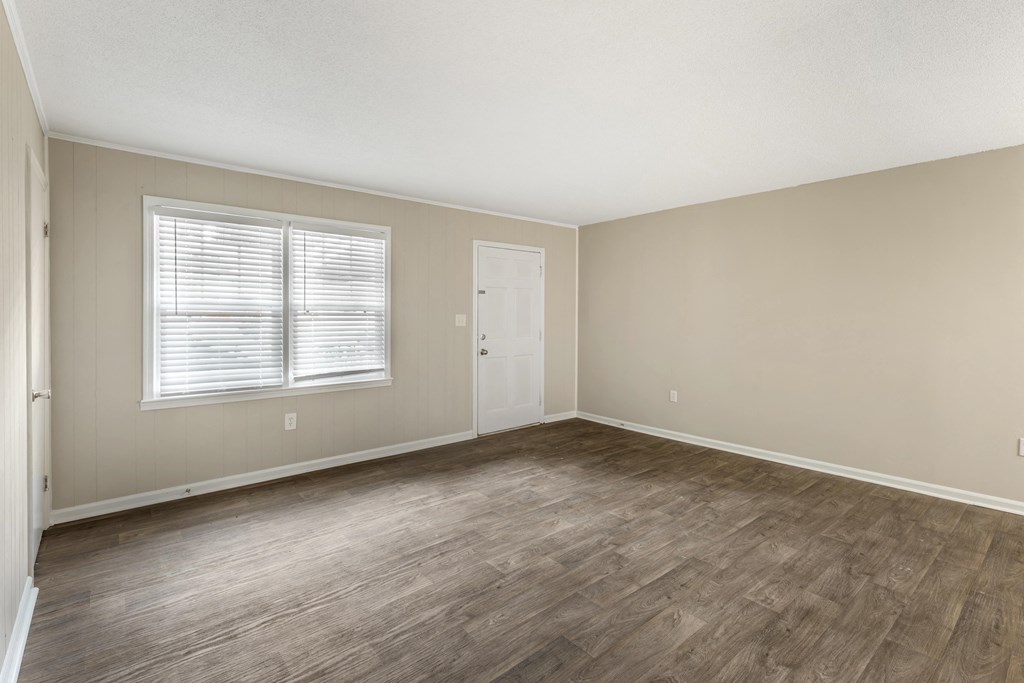 an empty living room with wood flooring and a window