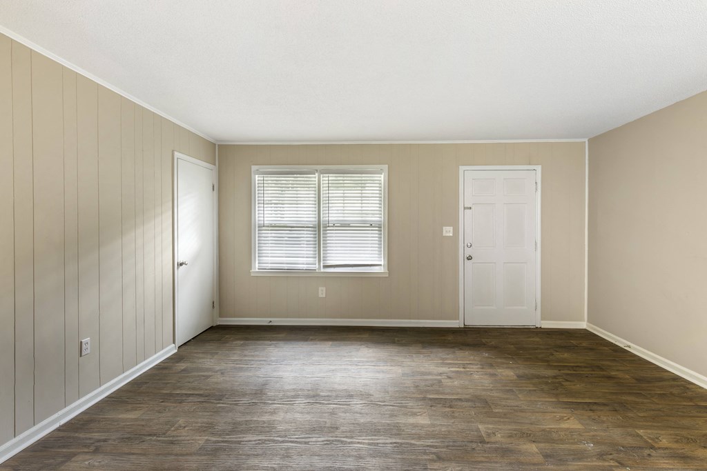 an empty living room with wood floors and a white door