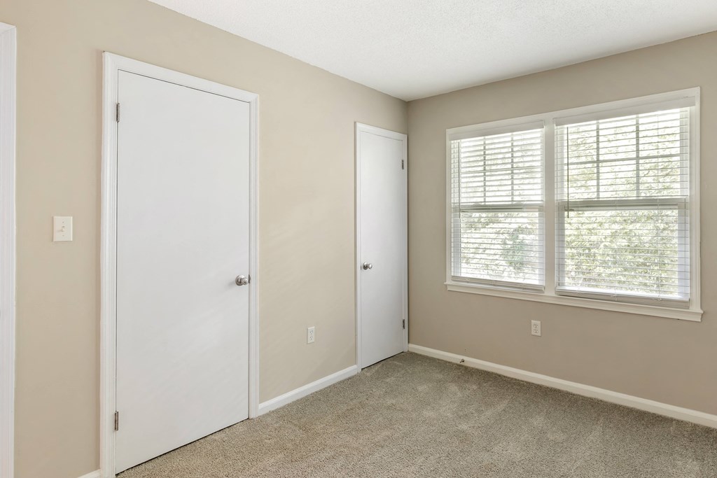 an empty bedroom with two doors and a window