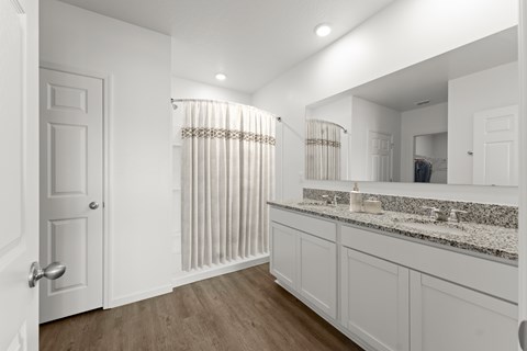 A white bathroom with a wooden floor and a mirror above the sink.