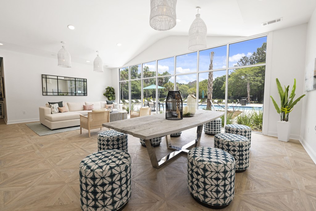 a living room with a large wooden table and stools in front of a large window