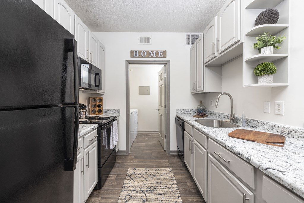 a kitchen with white cabinets and black appliances