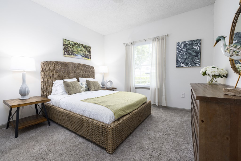 a bedroom with a large bed and a dresser with a lamp