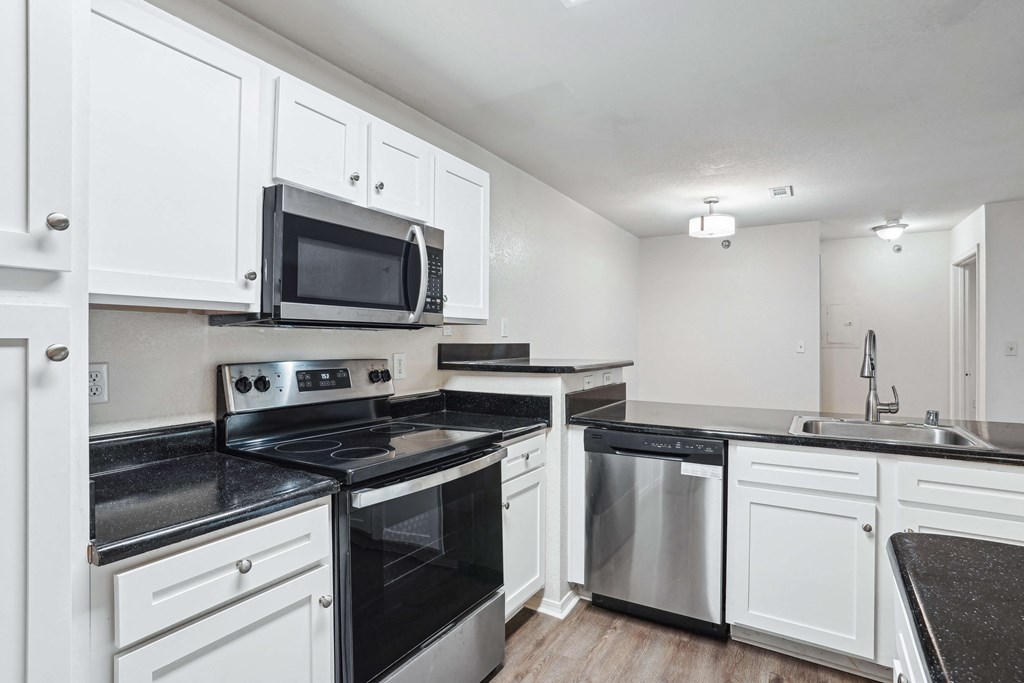 Apartments for Rent in Little Rock, AR 72223– Capitol Hill -   A kitchen with white cabinets and black countertops.